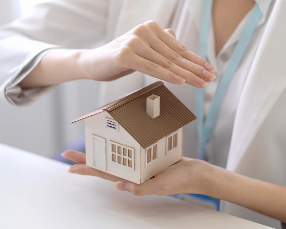 Cropped shot of a woman holding a house model
